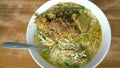 Indonesian food soto in a bowl placed in a wooden table