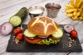 Delicious and inviting round sandwich with fresh vegetables. Light and healthy snack on a black stone cutting board, with french