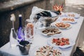 Delicious italian appetizers on table at wedding reception outdoors. Caviar, seafood, canapes, champagne and wine glasses on table