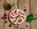 Delicious italian caprese salad with ripe tomatoes, fresh basil and mozzarella cheese on wooden rustic background. Italian caprese Royalty Free Stock Photo