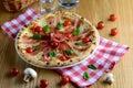 Delicious italian pizza with cream sauce, prosciutto, mozzarella, cherry tomatoes and basil, served on a wooden table for a dinner Royalty Free Stock Photo