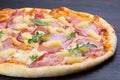 Delicious italian pizza with fresh tomatoes pineapples olives ham and basil on an old wooden board Royalty Free Stock Photo