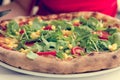 Delicious italian styled vegetable pizza with tomatoes, corn and rucola.