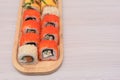 Delicious Japanese rolls with salmon, avocado, cucumber, cheese on wooden plate with selective focus. Asian food concept Royalty Free Stock Photo