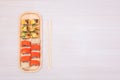 Delicious Japanese rolls with salmon, avocado, cucumber, cheese on wooden plate with wood sticks with selective focus Royalty Free Stock Photo