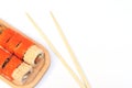 Delicious Japanese rolls with salmon, avocado, cucumber, cheese on wooden plate with wood sticks with selective focus on Royalty Free Stock Photo