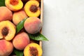 Delicious juicy peaches and leaves in crate on light grey textured table, top view. Space for text Royalty Free Stock Photo
