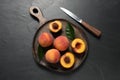 Delicious juicy peaches, leaves and knife on black textured table, top view Royalty Free Stock Photo