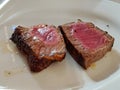 2 delicious and juicy pieces of medium steak served on a white plate.