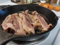 Delicious, juicy raw bacon cooking in a medium sized cast iron skillet Royalty Free Stock Photo