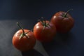 Delicious juicy tomatoes on a black background. Several tomato fruits in close-up