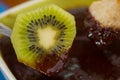 Delicious kiwi covered with chocolate fondue on wooden table