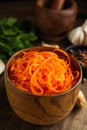 Delicious Korean carrot salad in bowl on wooden board