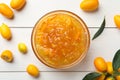 Delicious kumquat jam in bowl and fresh fruits on white wooden table, flat lay Royalty Free Stock Photo