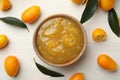 Delicious kumquat jam in bowl and fresh fruits on white wooden table, flat lay Royalty Free Stock Photo