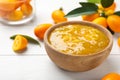 Delicious kumquat jam in bowl and fresh fruits on white wooden table, space for text Royalty Free Stock Photo