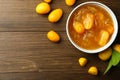 Delicious kumquat jam in bowl and fresh fruits on wooden table, flat lay. Space for text Royalty Free Stock Photo