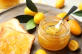 Delicious kumquat jam in jar, tasty toasts and fresh fruits on wooden board