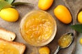 Delicious kumquat jam, tasty toasts and fresh fruits on wooden board, flat lay