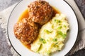 Delicious large meatballs with gravy with a side dish of mashed potatoes close-up in a plate. Horizontal top view