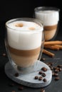 Delicious latte macchiato, cinnamon sticks and coffee beans on black table Royalty Free Stock Photo