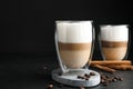 Delicious latte macchiato, cinnamon sticks and coffee beans on black table, space for text Royalty Free Stock Photo