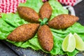 Delicious Lebanese food, kibbeh kibe with sauces and lemon on black slate stone and granite background with traditional keffyeh