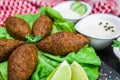 Delicious Lebanese food, kibbeh kibe with sauces and lemon on black slate stone and granite background with traditional keffyeh