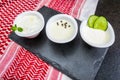 Delicious Lebanese food, thum, labneh and tzatziki sauces on black slate stone background and traditional Lebanese Keffiyeh turban