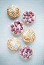 Delicious lemon and raspberry tartlets with meringue on a white vintage plate. Sweet treat on a light blue background. Flat lay an Royalty Free Stock Photo