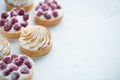 Delicious lemon and raspberry tartlets with meringue on a white vintage plate. Sweet treat on a light blue background. Flat lay an Royalty Free Stock Photo