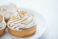 Delicious lemon tartlets with meringue on a white vintage plate. Sweet treat on a light blue background Royalty Free Stock Photo