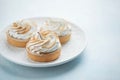 Delicious lemon tartlets with meringue on a white vintage plate. Sweet treat on a light blue background Royalty Free Stock Photo