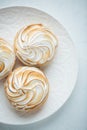 Delicious lemon tartlets with meringue on a white vintage plate. Sweet treat on a light blue background. Flat lay. Top view. Royalty Free Stock Photo