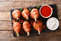 Delicious Lollipops chicken legs wrapped in bacon with sauces close-up on a slate board. horizontal top view Royalty Free Stock Photo