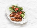 Delicious lunch, appetizer, tapas - chicken kebabs and fresh vegetable cucumbers tomatoes salad on a light background, top view