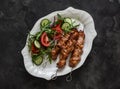 Delicious lunch, appetizer, tapas - chicken skewers and fresh vegetable salad on a dark background, top view