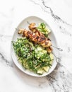 Delicious lunch - chicken bacon skewers and couscous, avocado, arugula salad on a light background top view
