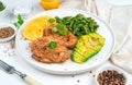 Delicious lunch with chicken steak and garnish with beans and avocado on a light background. Royalty Free Stock Photo