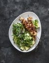 Delicious lunch, dinner - chicken bacon skewers and couscous, avocado, arugula salad on a dark background top view