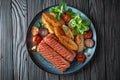 A delicious lunch or dinner of grilled meat sausages and baked potatoes with vegetables. Royalty Free Stock Photo