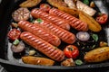 A delicious lunch or dinner of grilled meat sausages and baked potatoes with vegetables. Royalty Free Stock Photo