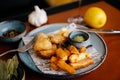 Lunch with fried potatoes, fish nuggets, green sauce, garlic, bay leaf and lemon on red table