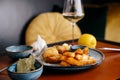 Lunch with fried potatoes, fish nuggets, green sauce, garlic, bay leaf and lemon on red table