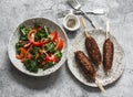 Delicious lunch - kale, tomatoes, sweet pepper salad and kebabs on a gray background, top view Royalty Free Stock Photo