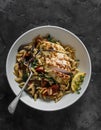 Delicious lunch - orzo with mushrooms, dried tomatoes, spinach and lemon thyme chicken breast on a dark background, top view Royalty Free Stock Photo