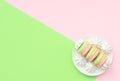 Delicious macarons with white merengues on white plate on double green and pink background. Happy day, breakfast, good morning