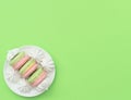 Delicious macarons with white merengues on white plate on green background. Happy day, breakfast, good morning concepts. Time for