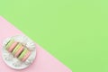 Delicious macarons with white merengues on white plate on double green and pink background. Happy day, breakfast, good morning