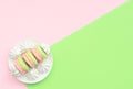 Delicious macarons with white merengues on white plate on double green and pink background. Happy day, breakfast, good morning